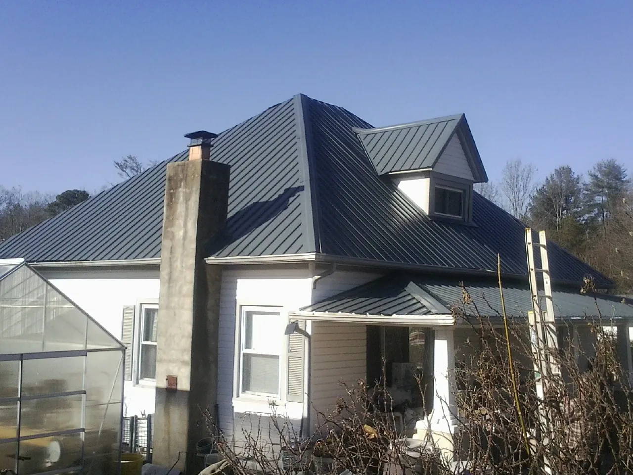 Dark blue standing seam metal roof on a white farmhouse with dormer — Slate & Tile Roof Repair by Roofing Brothers in Ninnekah