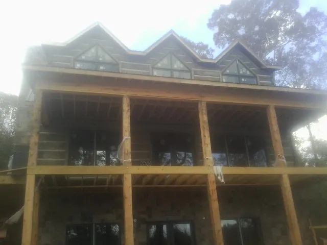 Dormers and porch framing on a large log home under construction — Roof Coating work by our crew in Ninnekah