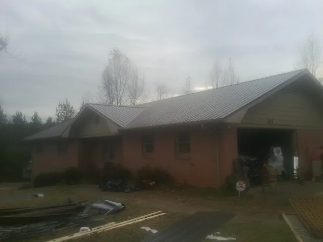 Gray metal roof on a stucco house with an attached garage in Ninnekah