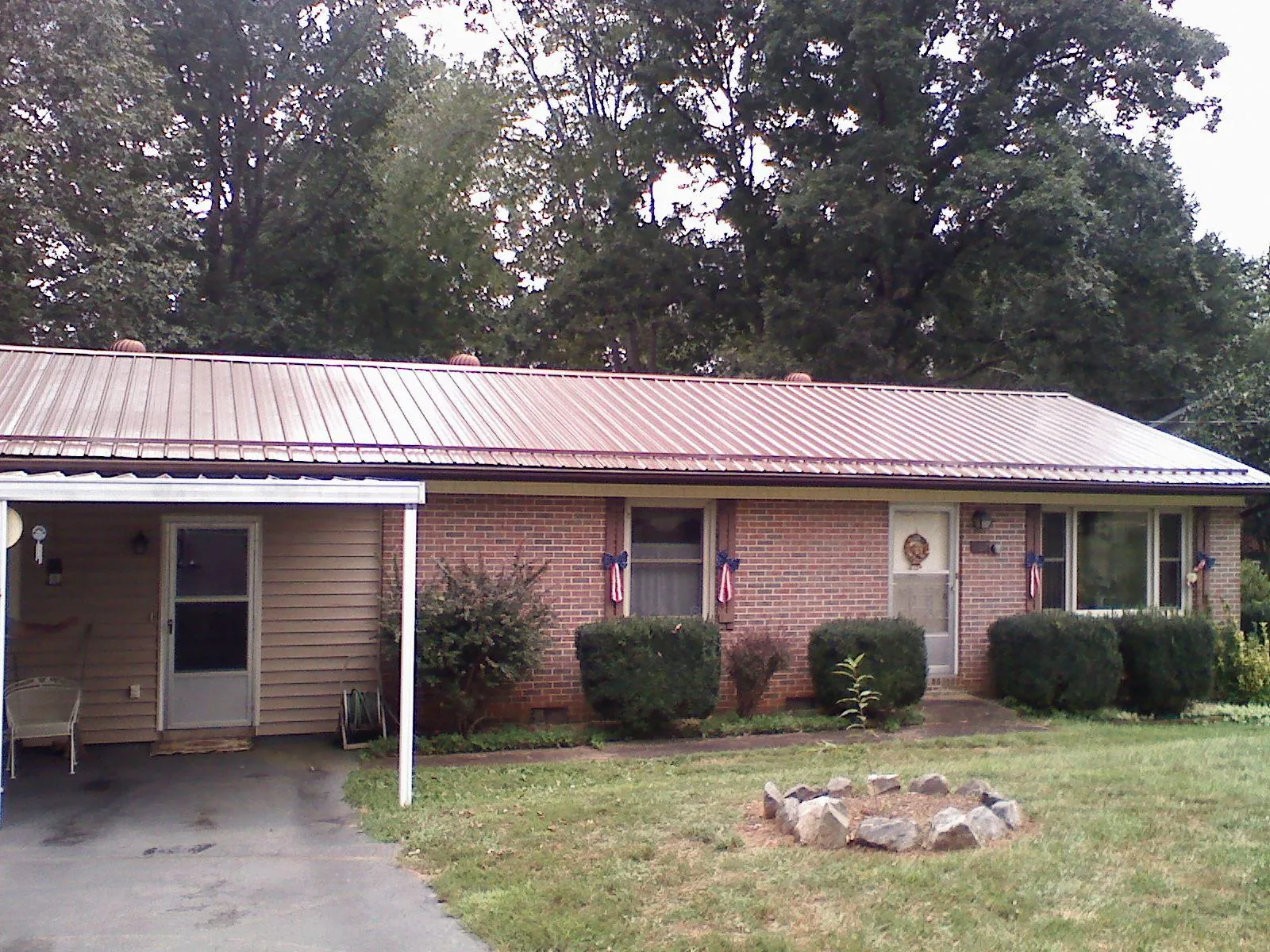 Bronze metal roof and carport on a brick ranch home — Roof Repair work by our crew in Ninnekah