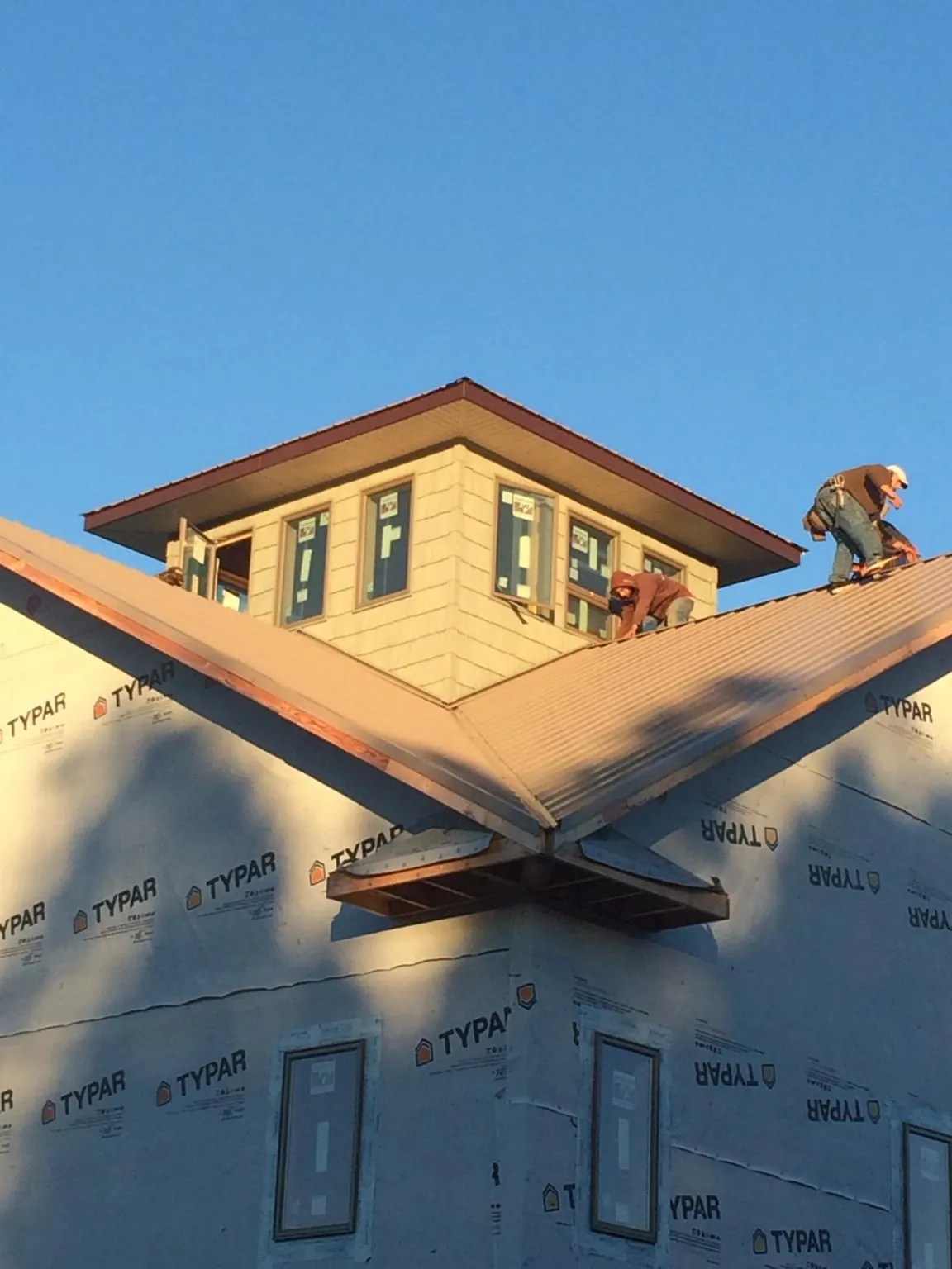 Roofers working around a rooftop cupola on a new metal roof at sunset — Roof Waterproofing in Ninnekah by Roofing Brothers